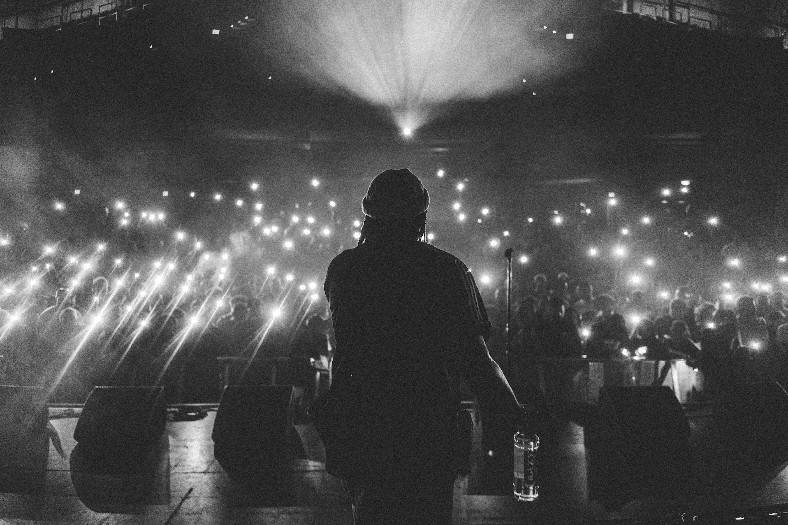 Rap artist on stage, with a crowd shining lights